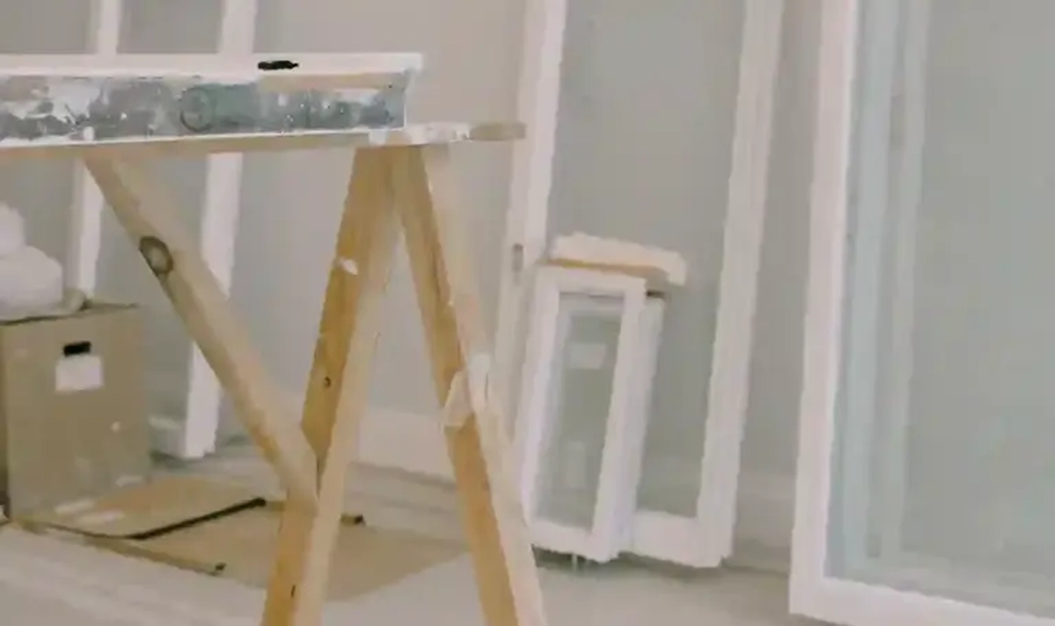 GM-Fensterbau - Fenster - Türen - Rollladen - In einem Raum, der gerade renoviert wird, hält ein hölzerner Sägebock ein mit Farbe bedecktes Brett.