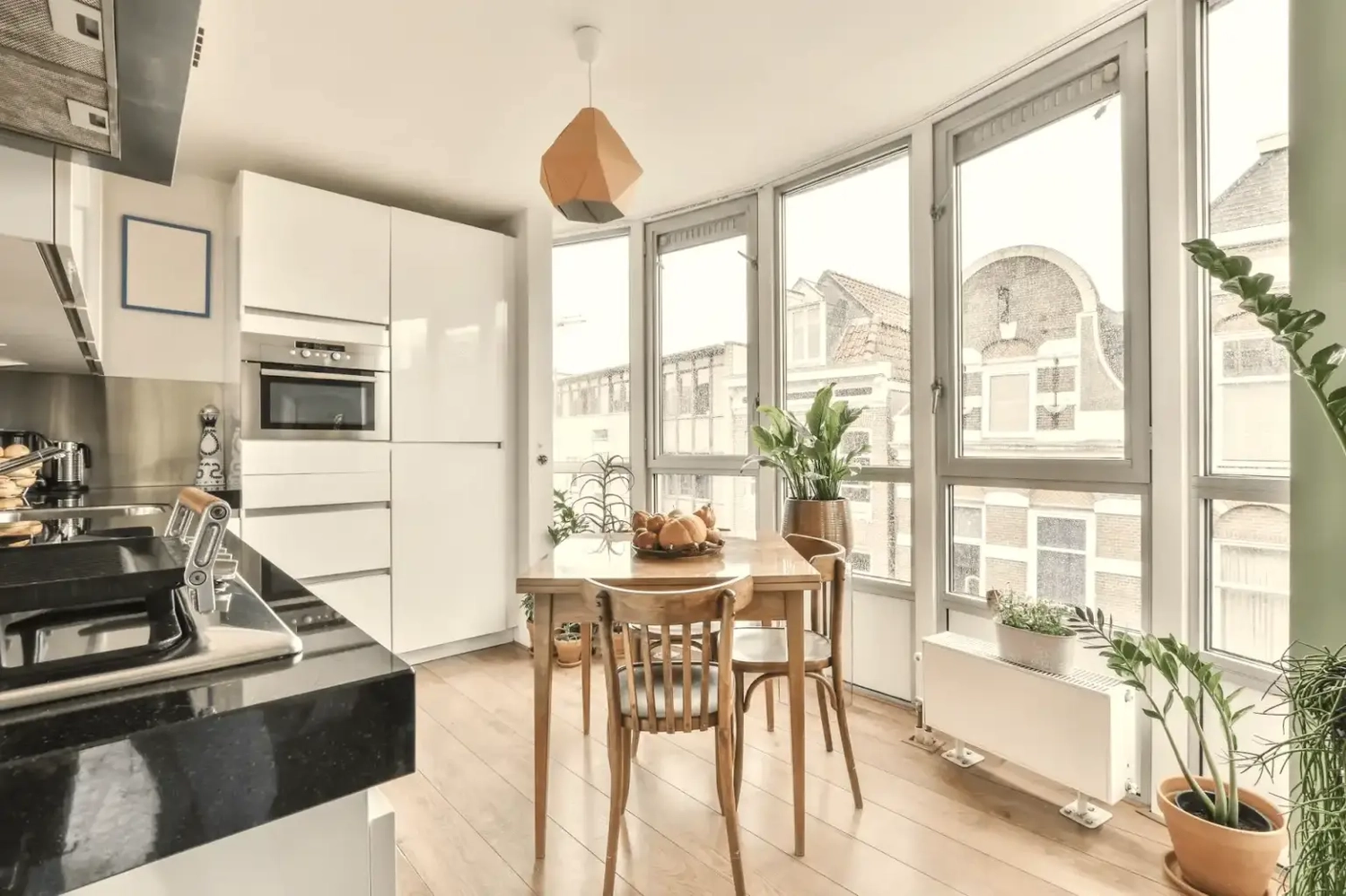 GM-Fensterbau - Fenster - Türen - Rollladen - Heller, moderner Küchen- und Essbereich mit bodentiefen Fenstern und Blick auf die Stadt.