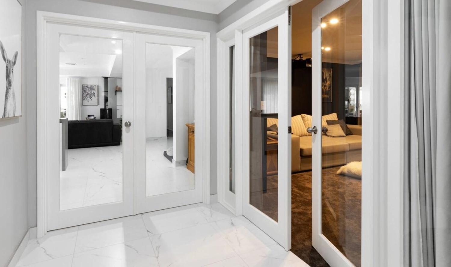 GM-Fensterbau - Fenster - Türen - Rollladen - Diese modernen weißen französischen Türen verfügen über große Glasscheiben, die den Lichteinfall zwischen den Wohnräumen ermöglichen.